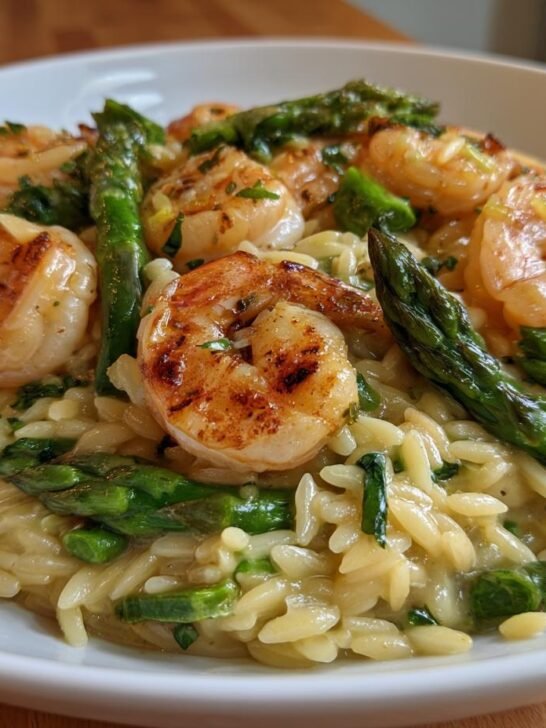 Close-up of Lemon Garlic Shrimp And Asparagus Orzo pasta topped with seared shrimp and bright green asparagus spears.