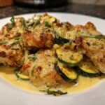 Close-up of golden brown chicken pieces and sliced zucchini coated in a creamy lemon parmesan sauce, part of the One Skillet Lemon Parmesan Chicken Zucchini.