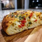 Close-up of a slice of Savory Caprese Bread showing melted mozzarella, bright red tomatoes, and fresh basil.