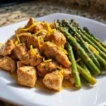 Plate of Sheet Pan Lemon Chicken With Asparagus topped with bright lemon zest.