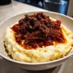 A generous serving of rich Short Rib Ragu With Parmesan Mashed Potatoes in a white bowl.