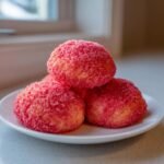 A stack of three bright pink Strawberry Crunch Cookies coated in crunchy red sugar crystals.