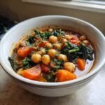Close-up of a bowl filled with Tuscan Garbanzo Bean Soup featuring chickpeas, carrots, and kale.