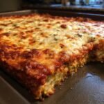 Close-up of a freshly baked Zucchini Pizza Casserole in a baking pan, topped with bubbly red sauce and melted mozzarella cheese.